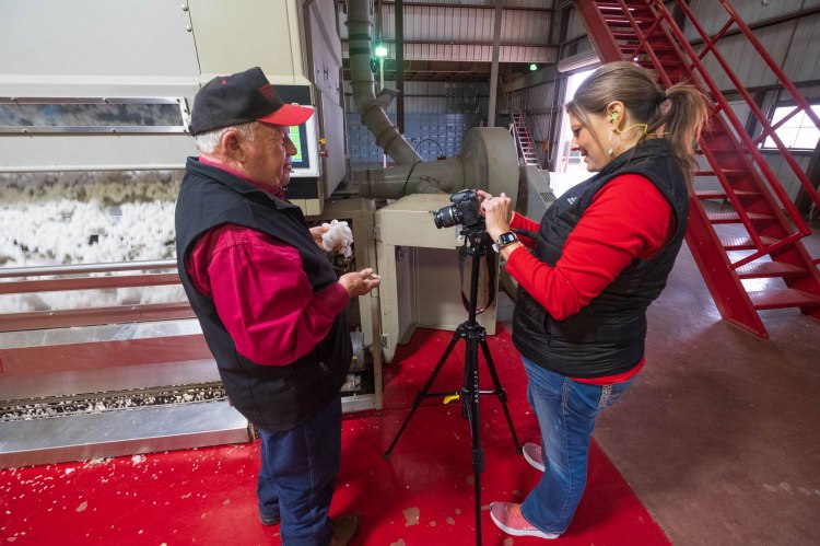 A photographer recording a cotton farmer in a cotton gin.