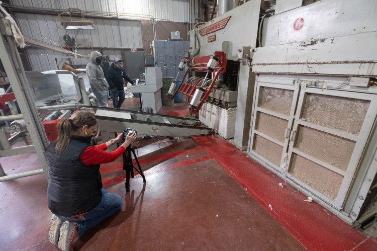A photographer recording video in a cotton gin.